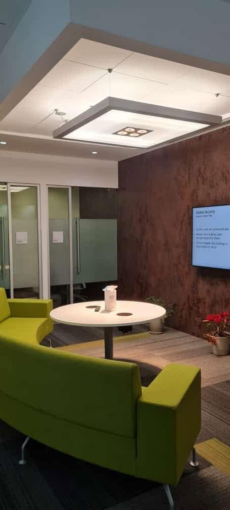 Sala de oficina con luminaria de panel en el techo y sillón verde